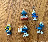 Photo of five vintage Smurf figurines on wood surface