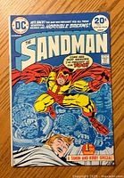 Front cover of The Sandman #1 comic book showing main character in red and yellow costume, cover price 20 cents, DC Comics logo and text.