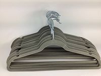 Stack of 20 grey felt clothing hangers with silver metal hooks, displayed from side.