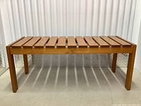 Front view of wooden slatted bench showing slat design and four legs.