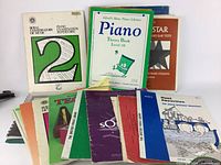 Overview photo of multiple piano and music theory training books showing the variety of educational material in the box.