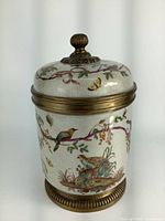 Close-up of the ceramic biscuit jar showing bird and butterfly design on crackled glaze surface with brass fittings