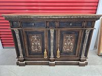Front view of Hekman buffet credenza showing ornate panel carvings, carved columns, and two cabinet doors with tassels.