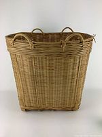 Front view of tall woven basket showing rectangular shape and looped handles