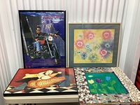 Four assorted vintage art prints displayed upright and flat, including motorcycle photo, floral painting, cubist woman painting, and mosaic framed tulip print.