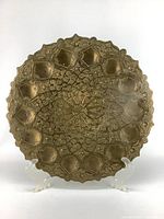 Full frontal image of the large stamped brass dish showing the detailed geometric and floral pattern and scalloped border