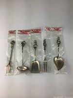 Set of 5 vintage sterling silver spoons, each individually packaged with Reed & Barton sterling label, showing all utensils aligned horizontally.