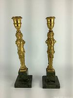 Pair of vintage brass candlesticks with cherub figures on green marble bases shown side by side.
