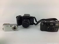 Three vintage cameras together: Pentax DSLR, Pentax Espio 738, Sony Cybershot
