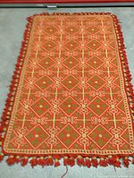 Full view of the vintage hand knotted rug showing reddish-orange geometric pattern and fringes