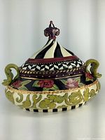 Front view of the colorful hand-painted soup tureen featuring intricate geometric and floral patterns with two handles and a finial top on lid.