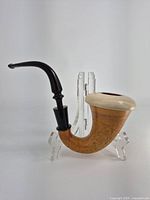 Side view of the vintage Sherlock Holmes style calabash pipe showing wood-textured bowl and curved black stem on clear stand.