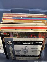 Photo showing 45 vintage record albums stacked vertically, titles mainly Judaica music, various colorful covers.