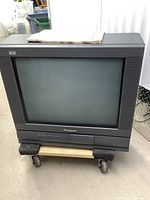 Front view of the vintage Panasonic CRT TV showing screen and overall condition on a wheeled dolly.