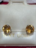 Front view of two round citrine earrings set in 10KT gold, displayed in the original holder marked '10 KT GOLD'