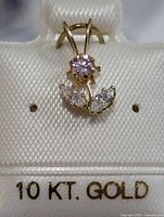 Another angled view of the pendant highlighting the floral design and the 10 KT gold mark on the display card.