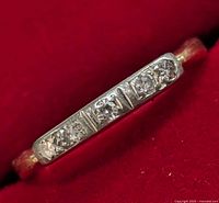 Front angled view on red background showing the five diamond setting