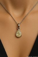 Pendant worn around neck showing pear-shaped yellowish natural diamond in 10KT gold setting on chain.