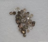 Loose small genuine diamonds in various colors and shapes placed on white fabric