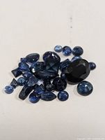 Loose genuine sapphire gemstones in various cuts and sizes displayed together for size and color comparison.