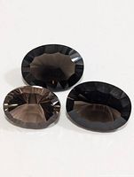 Three oval faceted smokey quartz gemstones in two slightly different positions and lighting