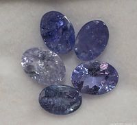 Close-up of five oval cut tanzanite stones showing color and inclusions