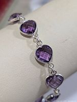 Close-up of the bracelet showing tear-drop shaped faceted amethyst stones set in silver links.