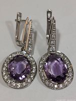 Front view of the silver earrings with amethyst and cubic zirconia stones showing oval purple amethysts surrounded by clear CZs.