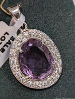 Front view of the silver pendant showing the oval faceted amethyst surrounded by cubic zirconia
