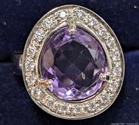 Close-up photo showing the front view of the silver ring with a cushion-cut amethyst center and clear CZ halo stones.