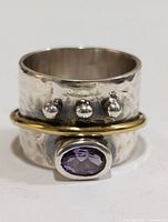 Front view showing hammered silver texture, three silver beads, oval amethyst stone set in bezel, and gold-tone accent band around wide silver band.