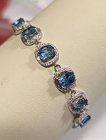 Close-up photo showing linked oval blue topaz stones with surrounding silver detailing on the bracelet.