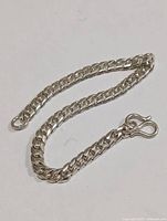 Silver curb chain bracelet, laid out straight on white background showing length and clasp.