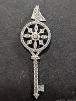 Front view of silver key-shaped pendant with cubic zirconia in starburst pattern and along shaft.