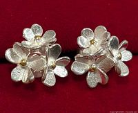 Close-up image of pair of silver floral earrings showing texture and gold-toned flower centers.