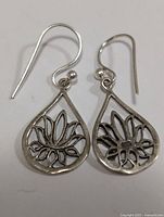 Pair of silver teardrop earrings with floral openwork design shown from front.