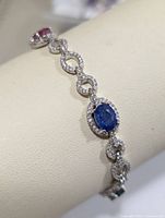 Close-up view of sapphire gemstone set in silver bracelet with clear small stones.