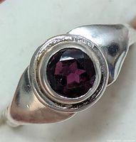Close-up of silver ring with round garnet stone from the front