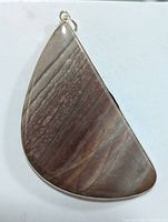 Front view of silver pendant with large polished brown natural gemstone with horizontal striations in silver bezel setting.