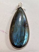 Front angled view of teardrop labradorite pendant with visible blue-green iridescence and silver bezel.