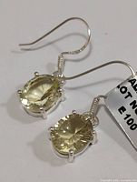 Pair of silver earrings with oval lemon quartz stones on fishhook attachments shown against a white background