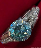 Close-up of the round-cut moissanite center stone on silver band with accent stones.