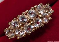 Close-up top angled view of silver ring with 1.1ct morganite stones arranged in two rows set with prongs on a red background.
