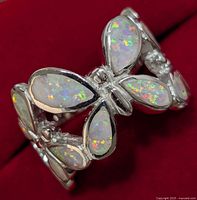 Close-up angle of silver butterfly ring with multi-color opalite stones showing detailed wing pattern and shiny silver band.