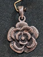 Front view of the silver flower pendant showing layered and textured petals with a polished silver bail for attaching to a necklace.