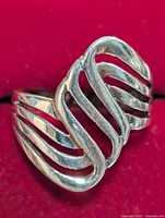 Close-up image of silver ring showing curved openwork bands and polished surface