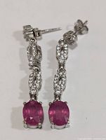 Front view of silver earrings showing ruby stones and CZ accents