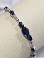 Close-up view of the sapphire stones and silver prong settings highlighting the gem color and clarity.