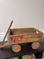 Side view showing red Royal Crown Cola branding on wood, wooden wheels, and angled pull handle.