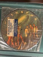 Front view of The Jacksons Victory picture disc vinyl record showing the group artwork and sticker with album details in original plastic sleeve.